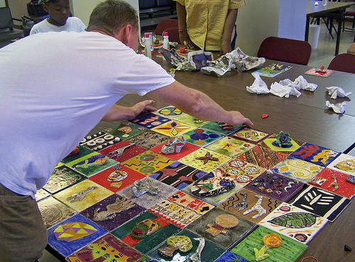 Patrick works on the layout of art tiles for the mural installation.